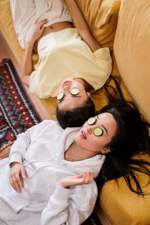 2 woman relaxing with cucumbers on their eyes