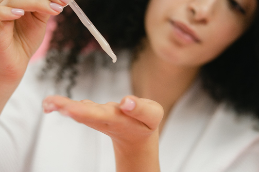 Woman using a dropper to put serum on her pal 