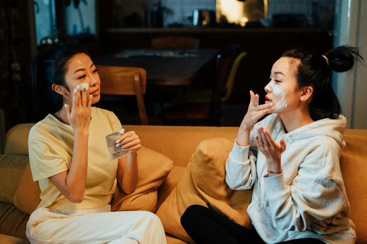Two young women putting crème on their faces 